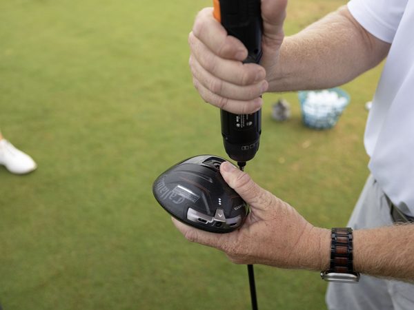 A fitter adjusting a driver head with a torque wrench