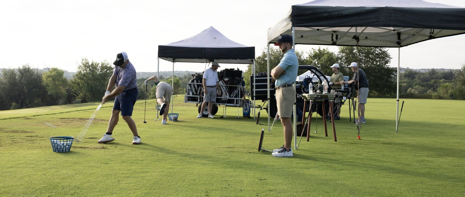 A golfer striking an iron shot off grass at Barton Creek, turf spray off the clubhead and the ball away down range