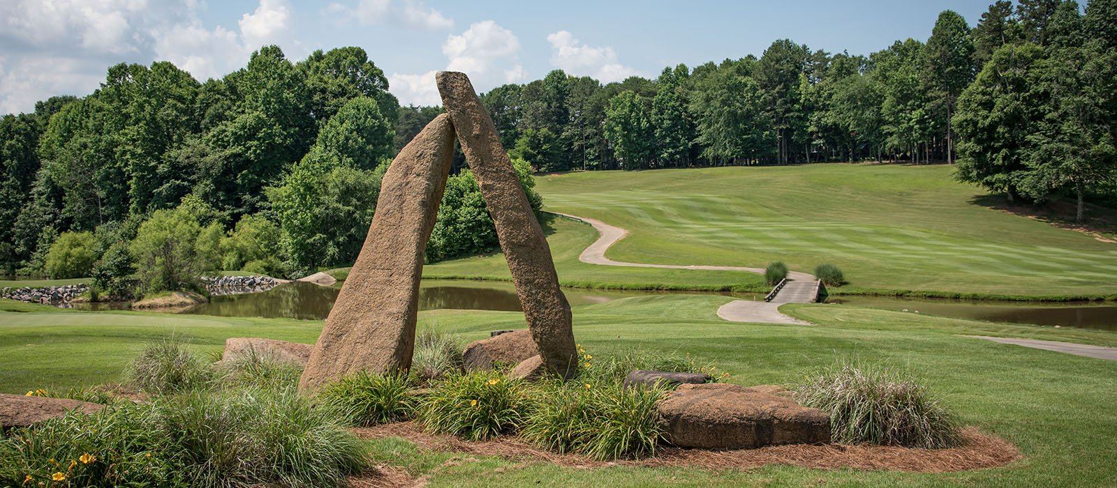 The stone sculpture at NorthStone Country Club in Charlotte, North Carolina, with the fairway, pond and cart bridge behind it