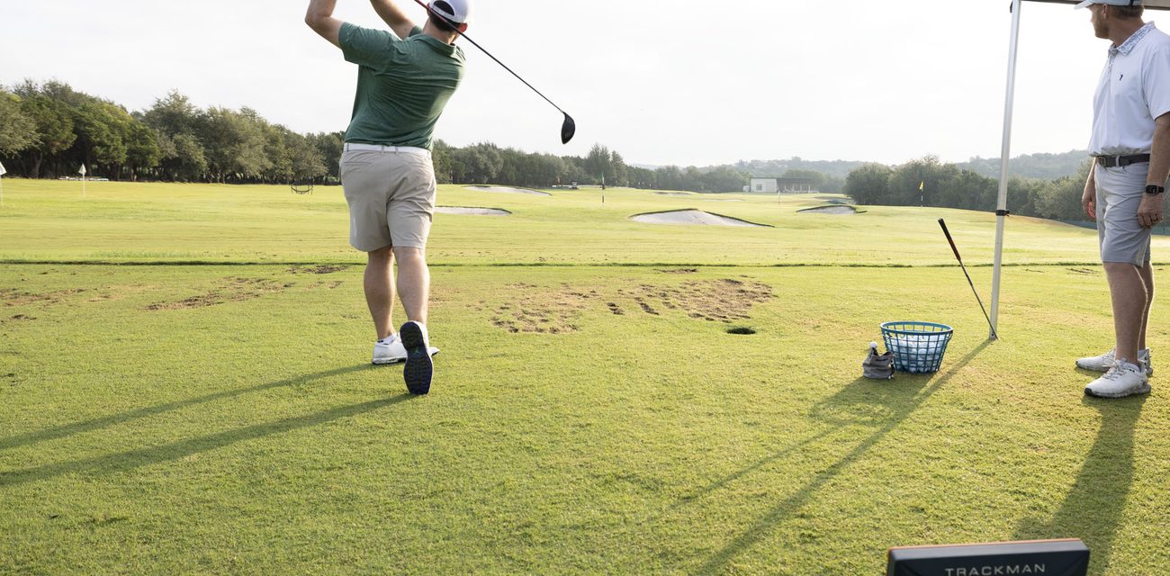 A customer hitting a driver on real grass at Barton Creek, with the Trackman unit in the foreground